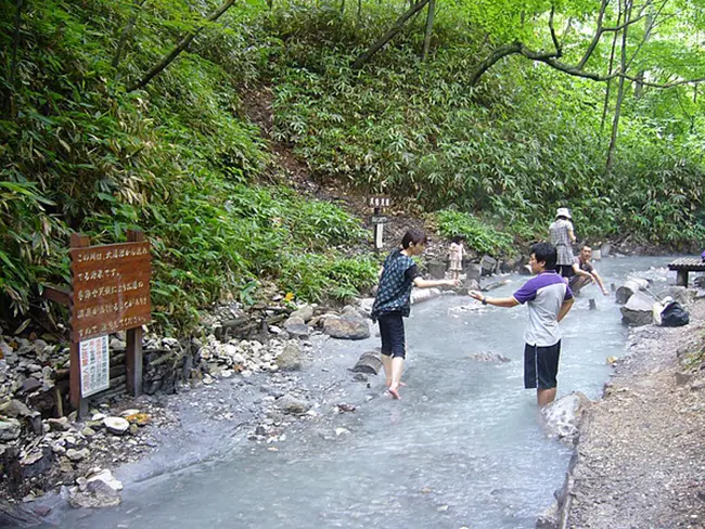 숲속을 흐르는 따뜻한 온천물에 발을 담그고 휴식을 취하는 오유누마 천연 족욕장