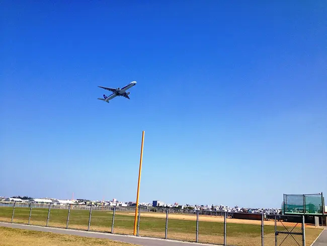 푸른 하늘을 가르며 우미카지테라스 위로 낮게 날아가는 대형 여객기