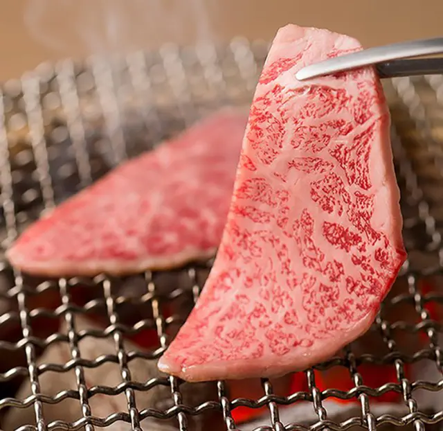 Premium wagyu beef cooking on a charcoal grill in Japan